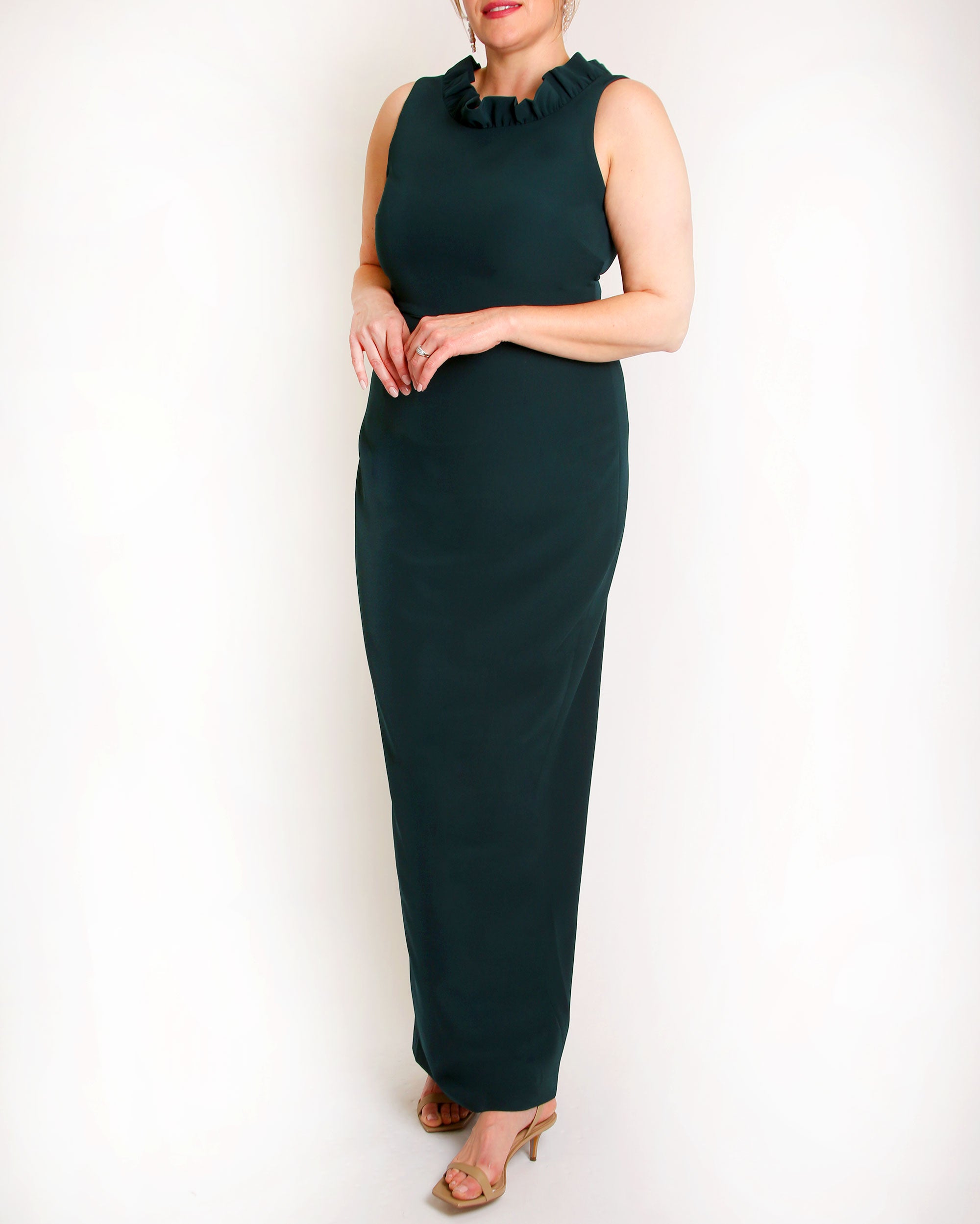 A floor-length sleeveless Evergreen gown with a ruffle neckline and a V-back detail, featuring a sheath silhouette made of stretch crepe fabric.