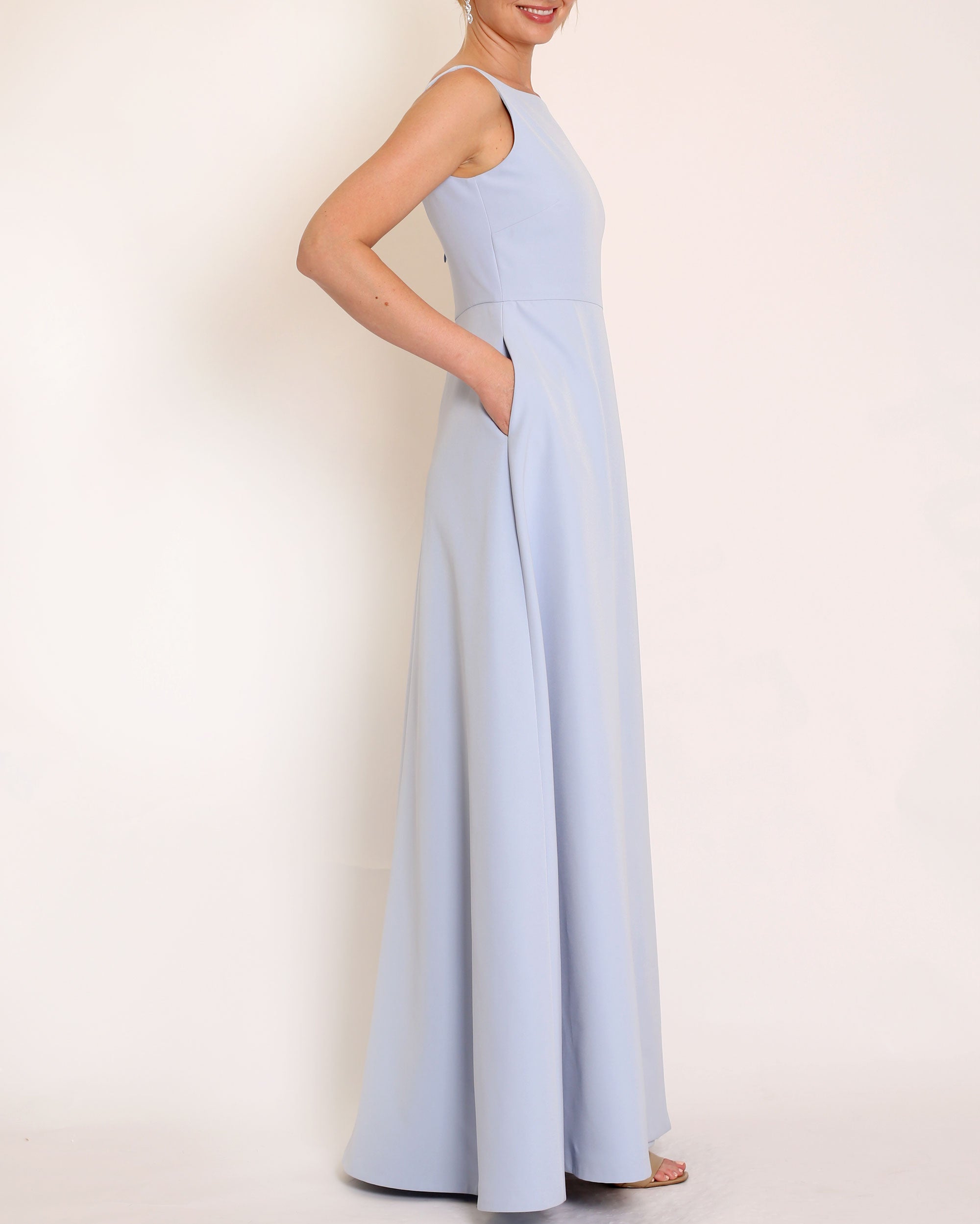 Light Blue floor length evening gown with boat neck detail and v-back. A-line flared skirt with front side slit and pockets.