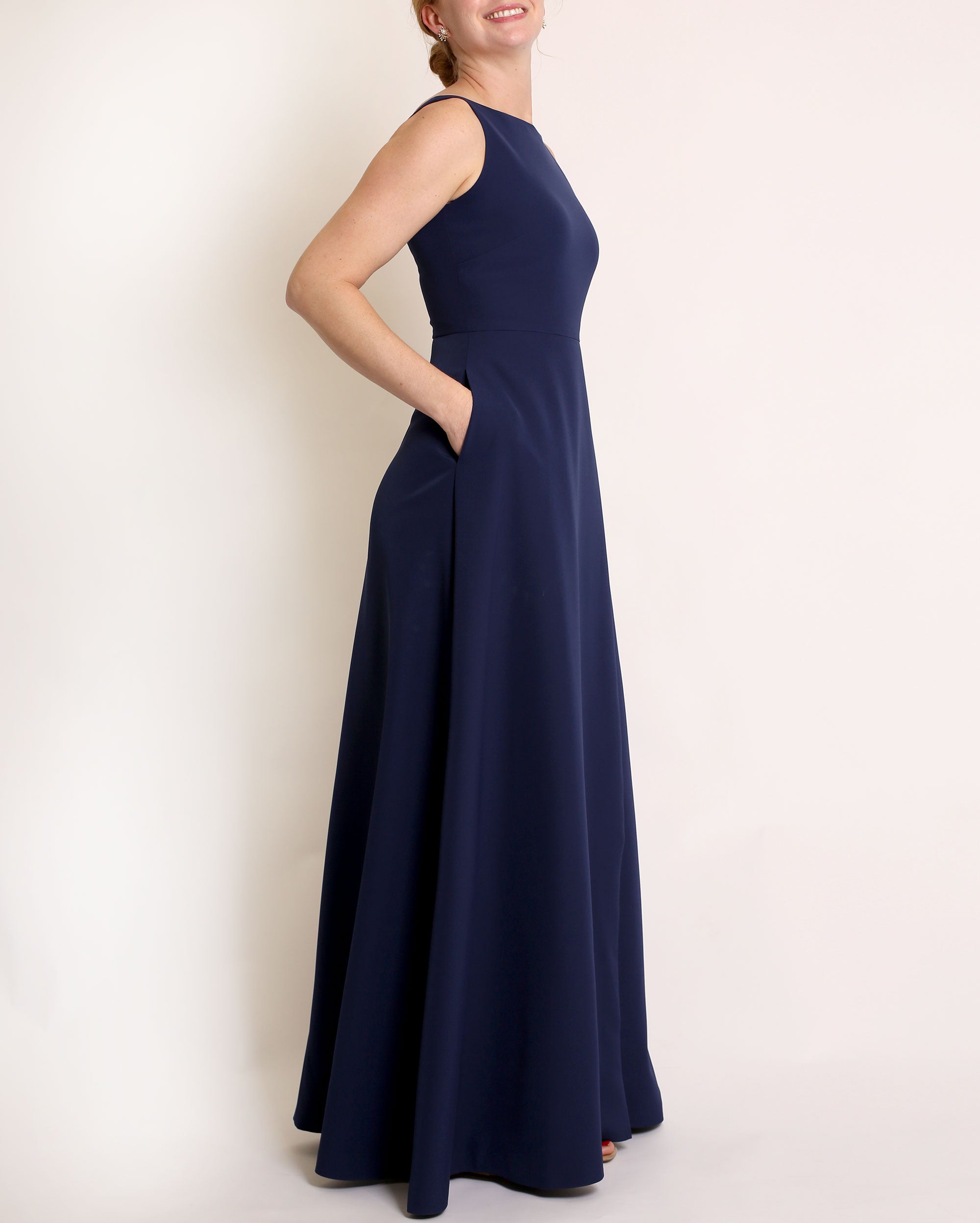Navy Blue floor length evening gown with boat neck detail and v-back. A-line flared skirt with front side slit and pockets.