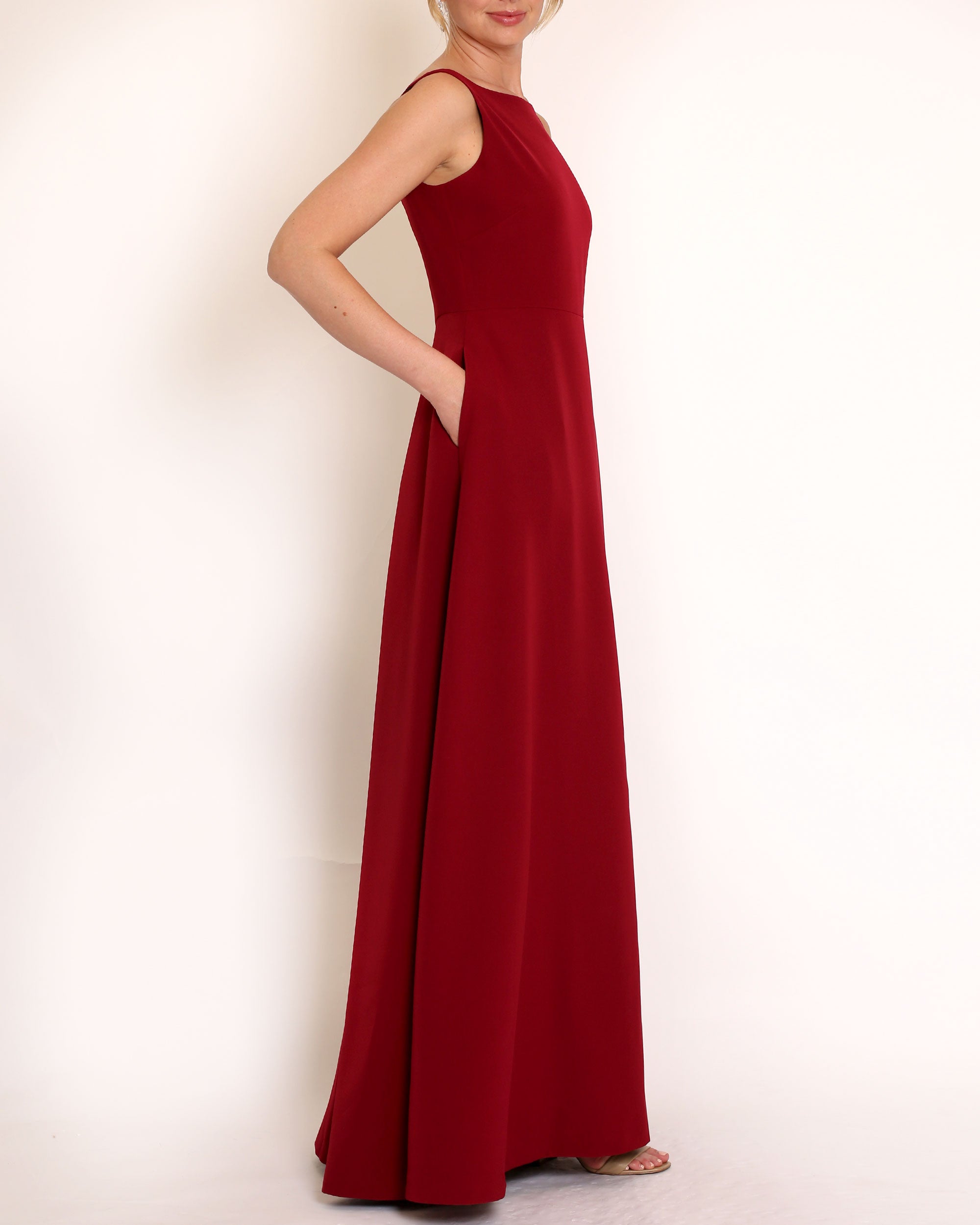 Burgundy floor length evening gown with boat neck detail and v-back. A-line flared skirt with front side slit and pockets.
