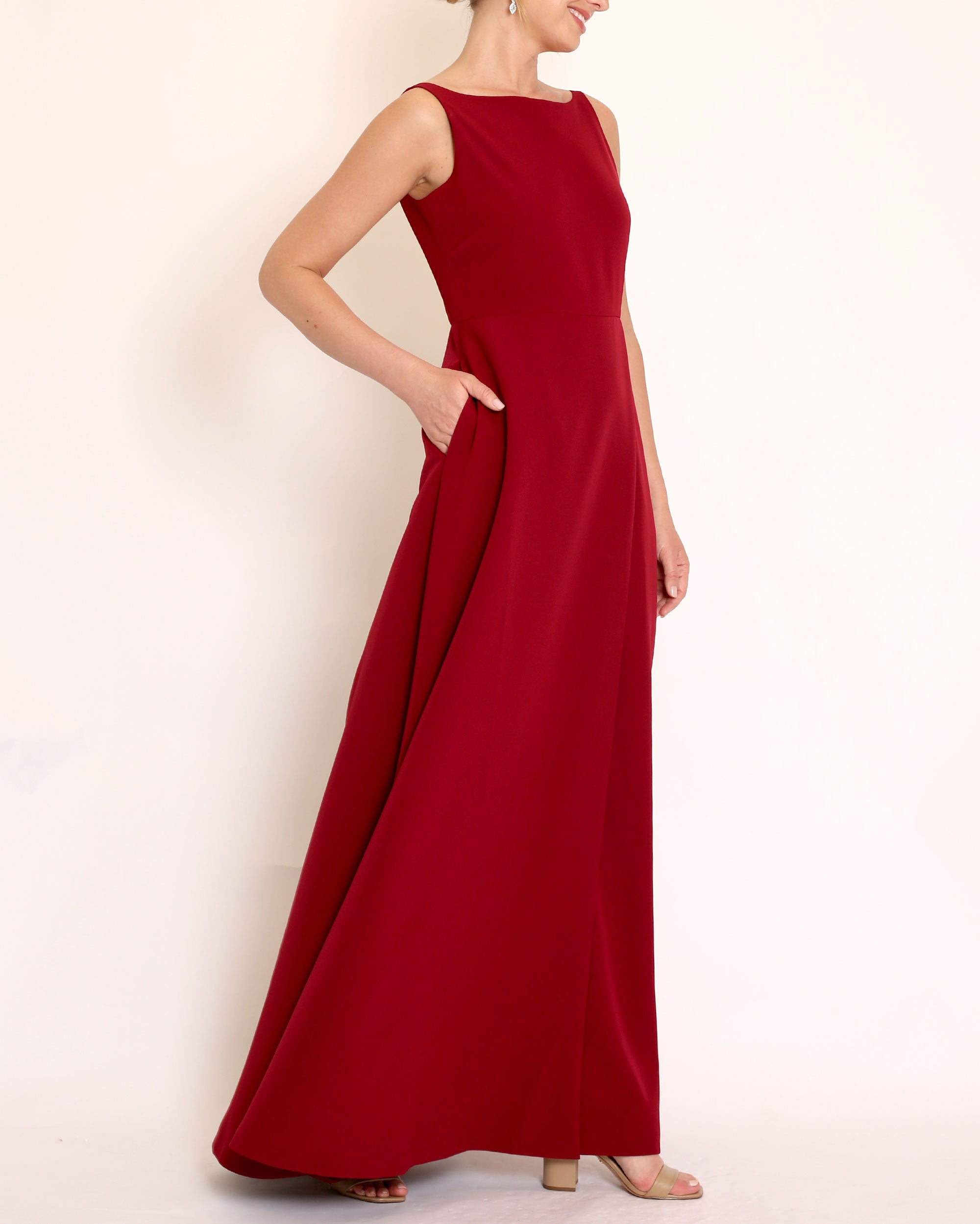 Burgundy floor length evening gown with boat neck detail and v-back. A-line flared skirt with front side slit and pockets.