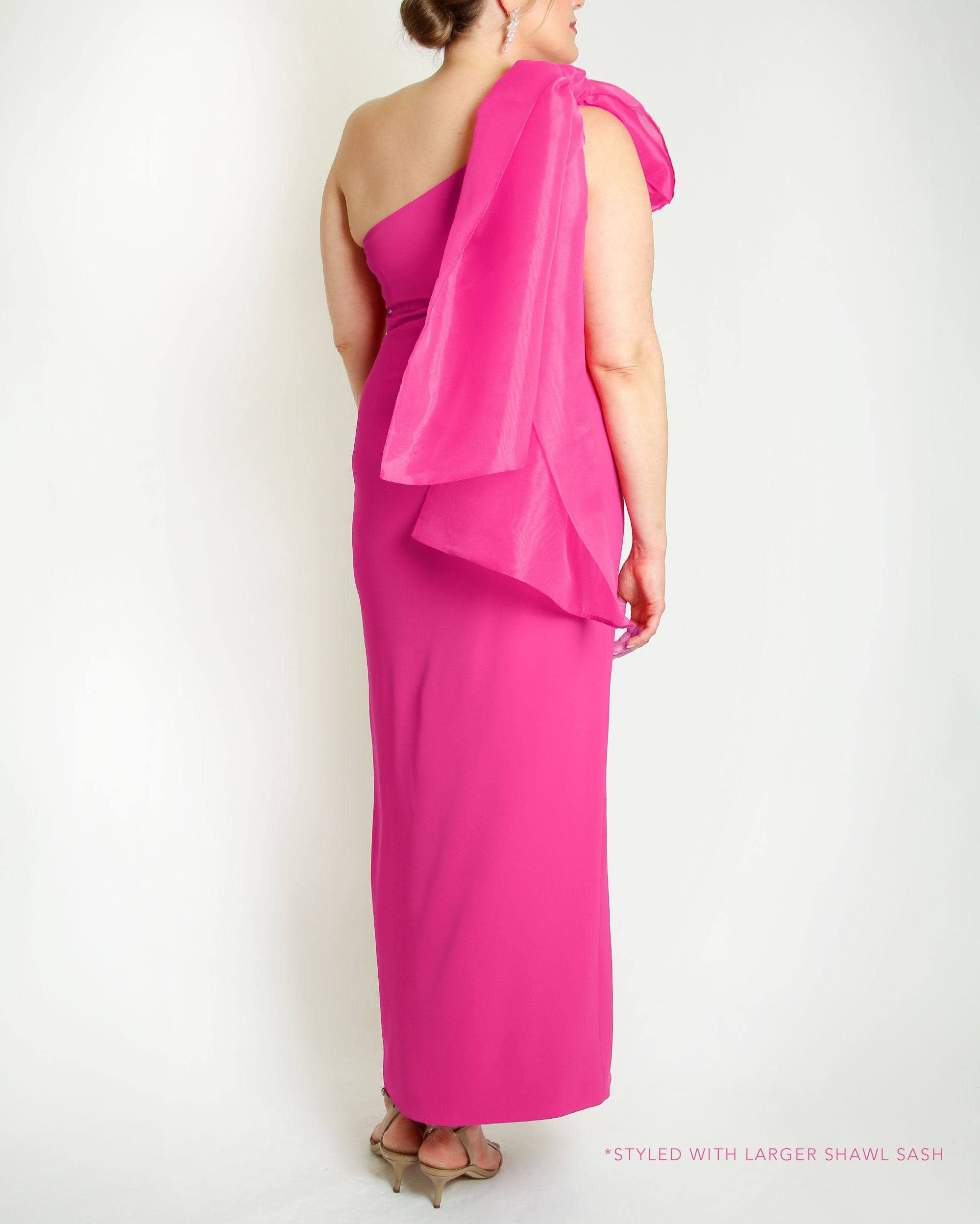 Fuchsia one-shoulder gown with a large bow detail on a white background