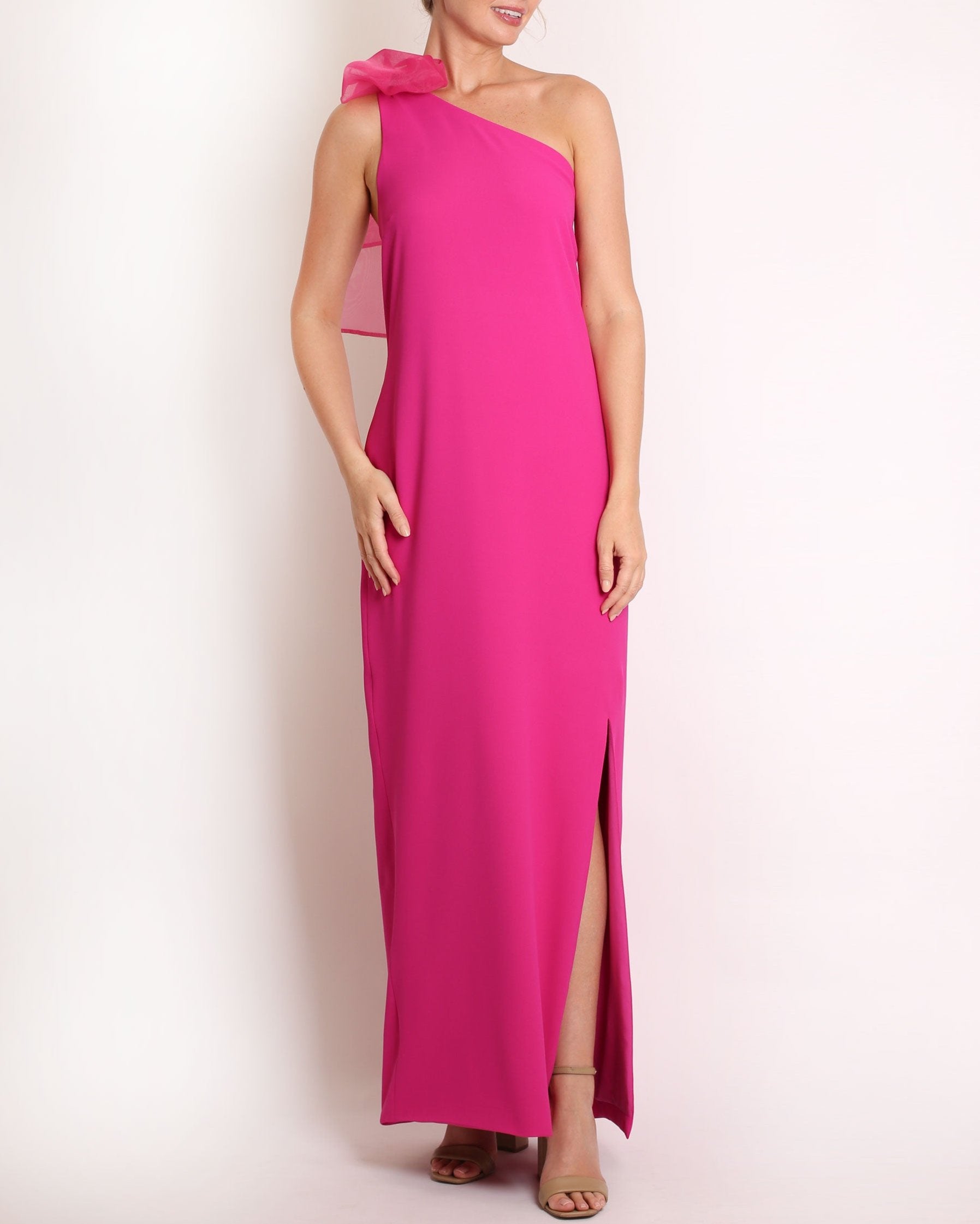 Fuchsia one-shoulder gown with a large bow detail on a white background
