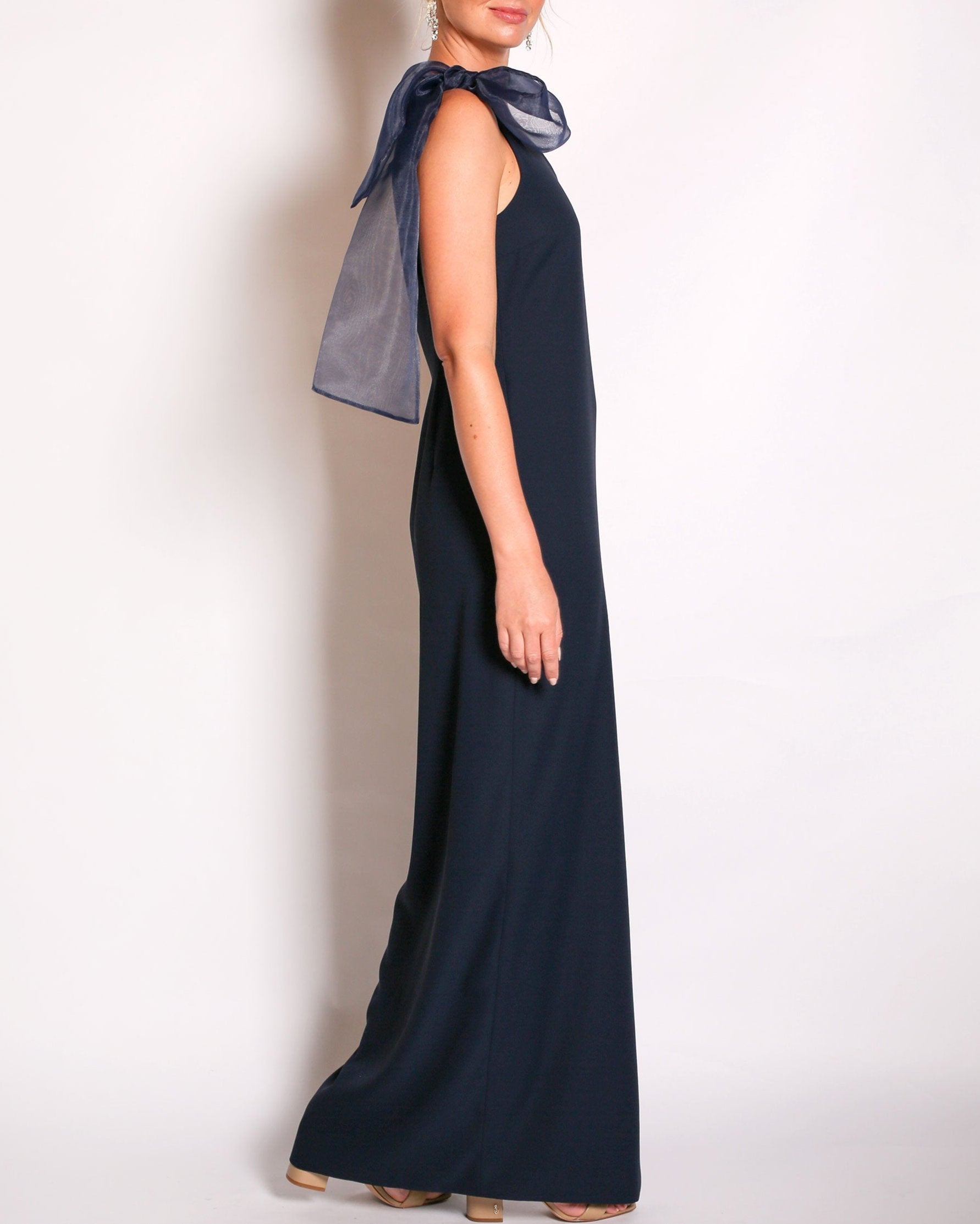 Navy one-shoulder gown with a large bow detail on a white background