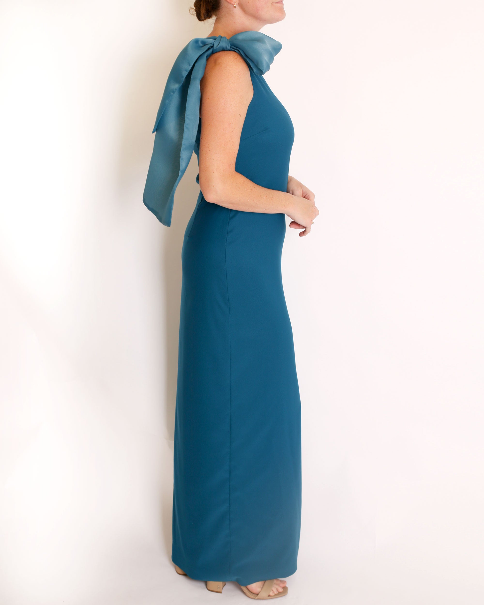 TEal one-shoulder gown with a large bow detail on a white background