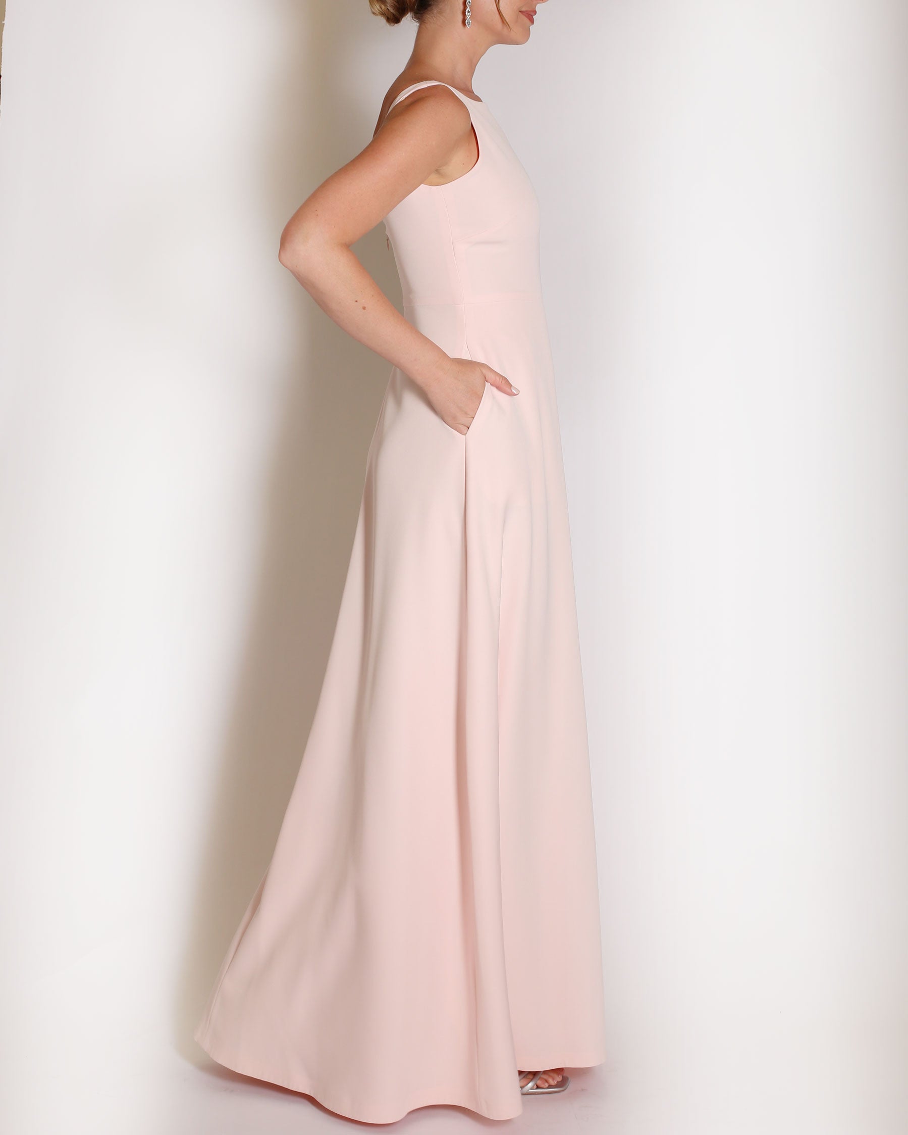 Light Pink floor length evening gown with boat neck detail and v-back. A-line flared skirt with front side slit and pockets.