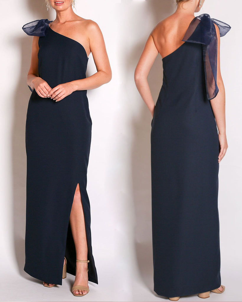 Navy one-shoulder gown with a large bow detail on a white background