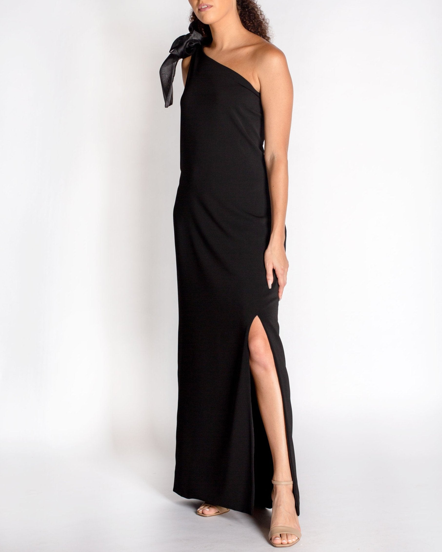 Black one-shoulder gown with a large bow detail on a white background